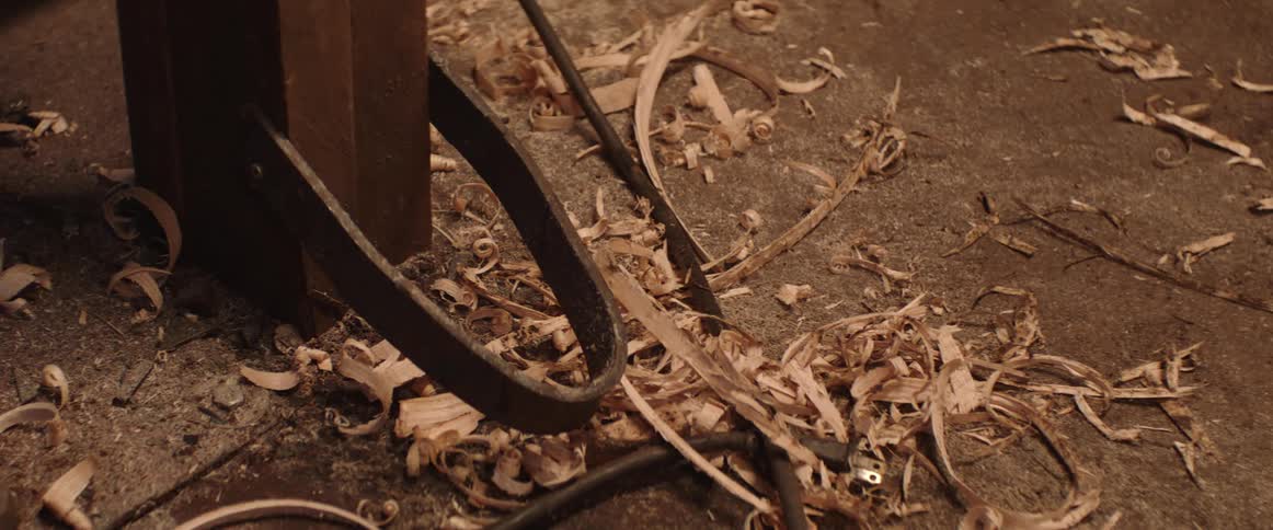 Close up of long wood shavings laying on the ground of a workshop