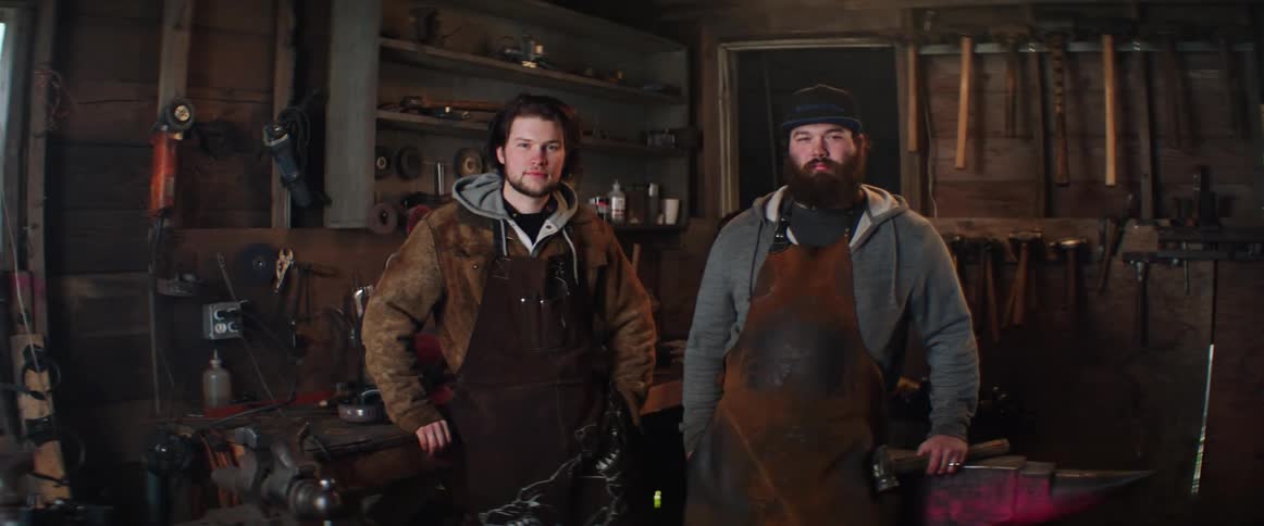 Portrait of two blacksmith men in their workshop surrounded by forging tools