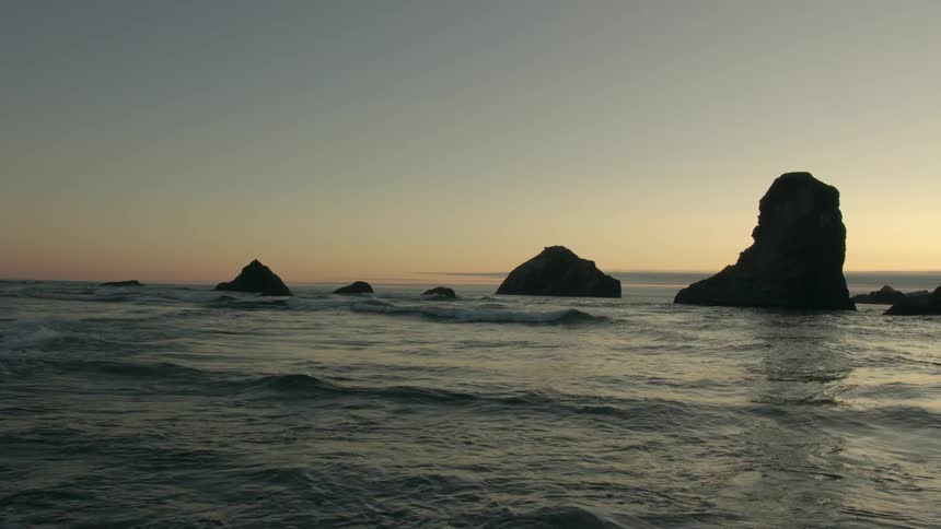 Waves rolling with rocks and the sunset in the background