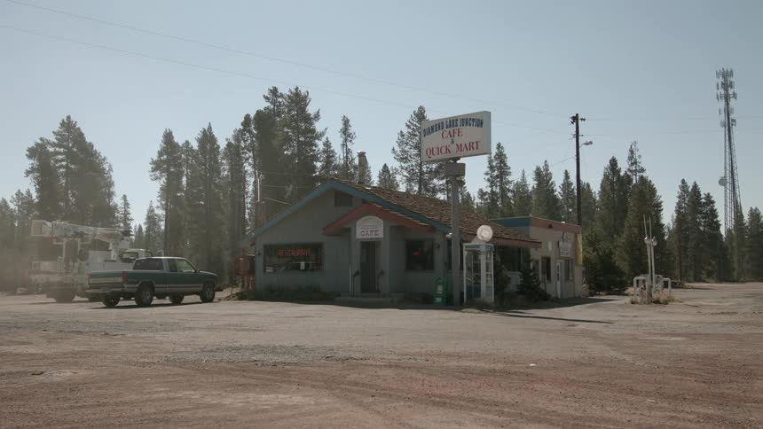 Two vehicles parked outside a cafe in a small town
