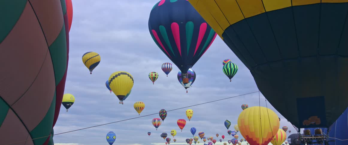 Dozens of colorful hot air balloons float through the sky