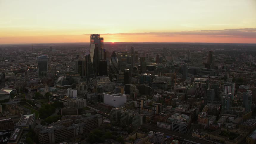 Tall buildings loom over a metropolis at sunset