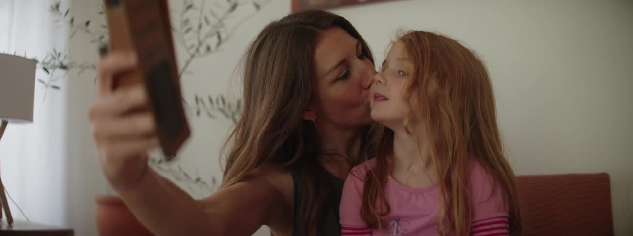 A mother and daughter in theliving room taking pictures from a phone