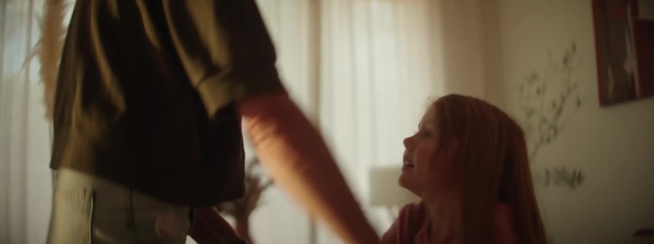 A woman is dancing in the living room with her young daughter