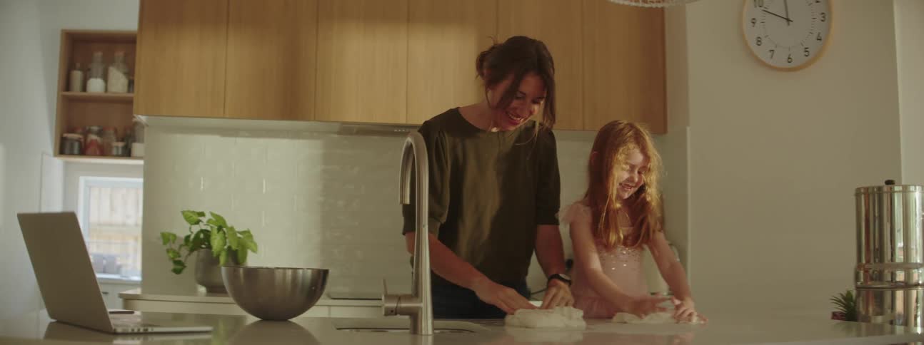 Mother and daughter kneading dough over the kitchen counter at home