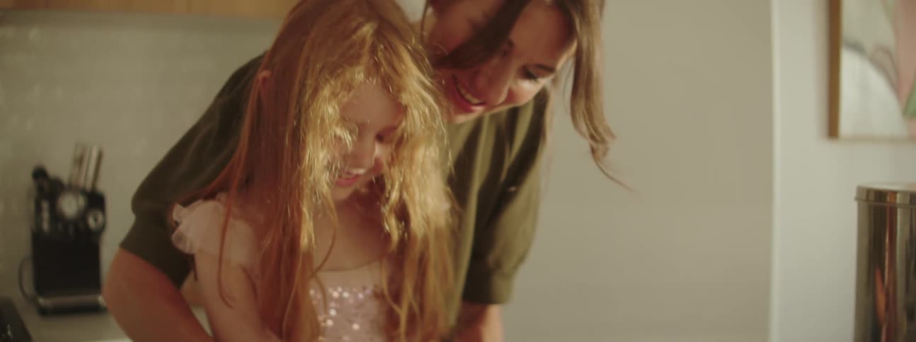 A mother and her daughter bake as they work with dough at home