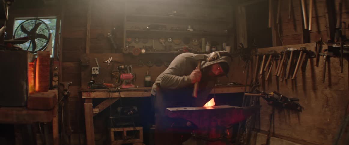 A man hammers hot steel in a blacksmith workshop