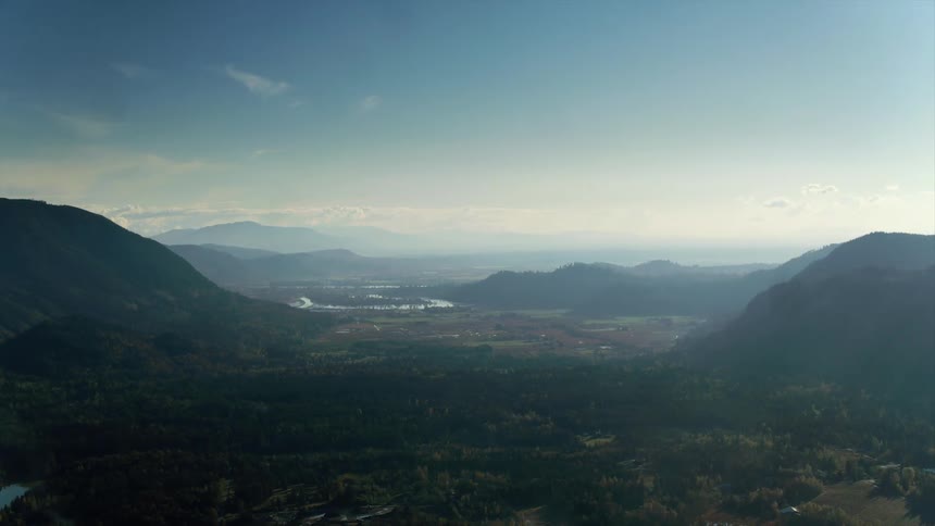 Aerial view of a hazy rural valley between two wooded mountain ranges