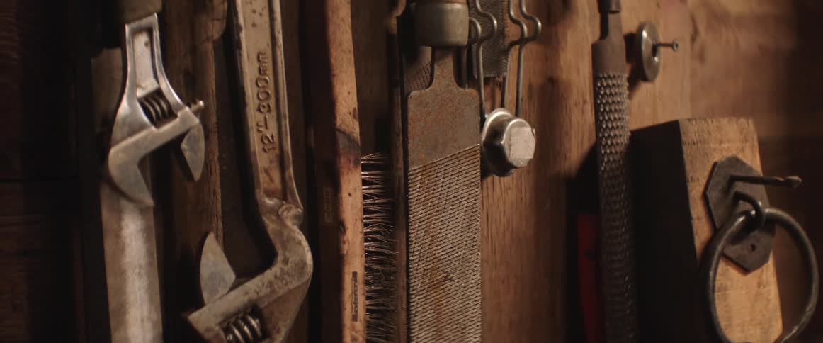 Wrenches and other tools are hanging on the wall in a workshop
