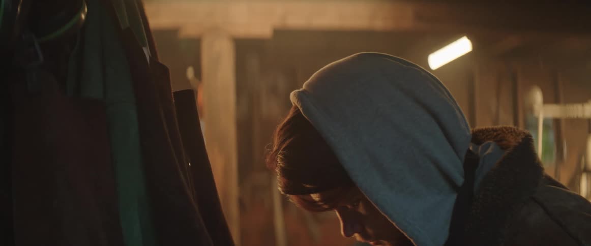 Young bearded blacksmith man wearing a hoodie picks on his apron after arriving at his shop