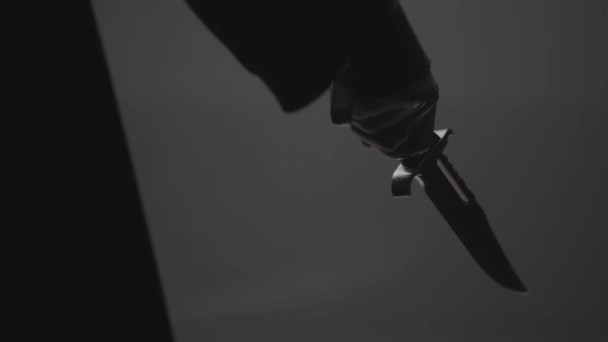 A person is holding a knife in a dim room
