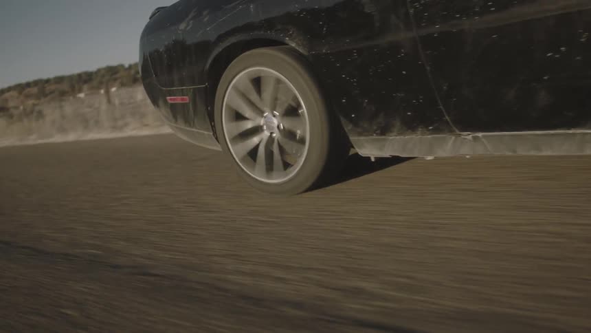 A black car is driving on a road