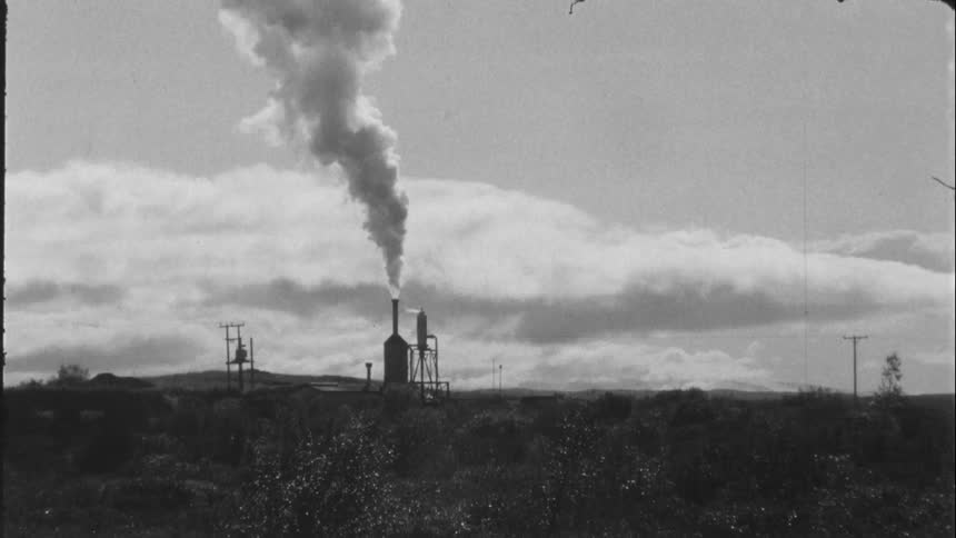 Smoke rises up through factory chimney in the field