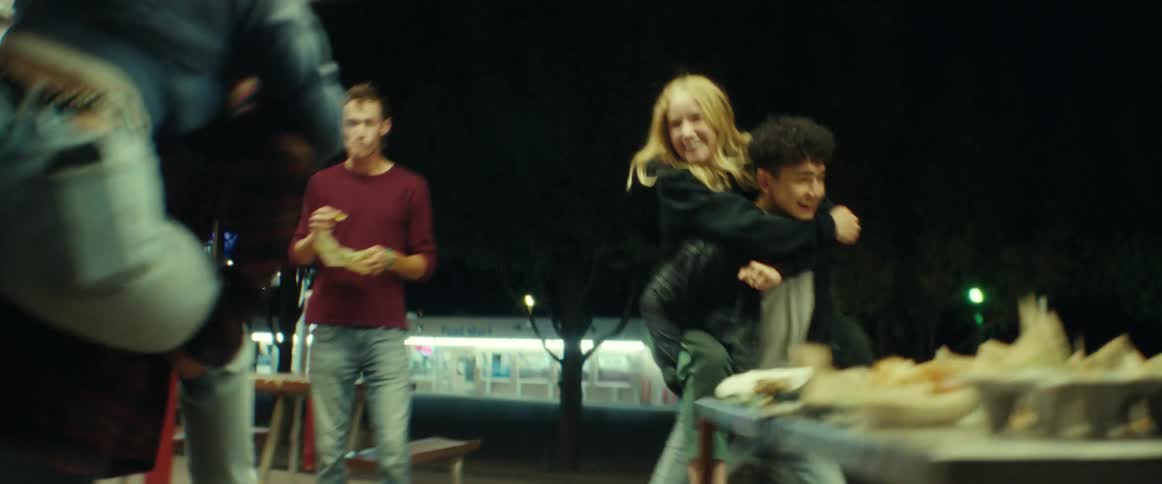 Teenagers run around on piggyback outside restaurant