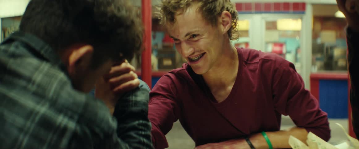 Group of friends arm wrestling on a table of a burger joint at night