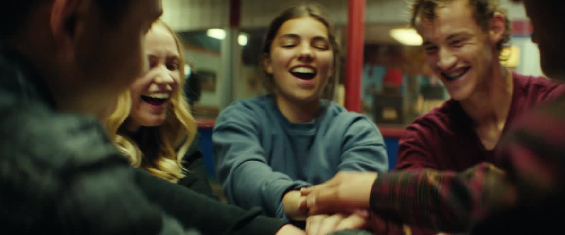 A group of teenagers are sitting at a table outside a fast food restaurant having fun