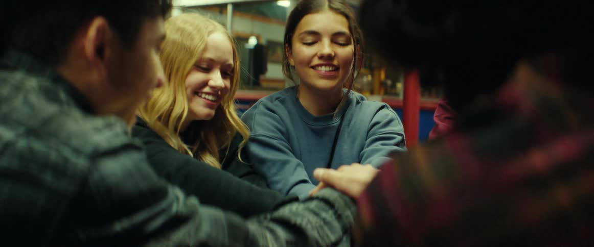 Group of friends playing hand clapping games outside of a diner at night