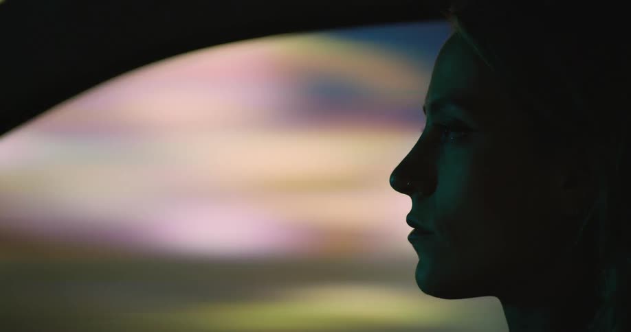 A woman driving at night with a blurred city background