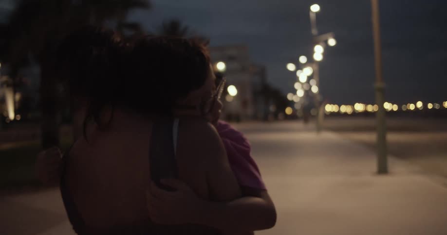 A woman is carrying her child on the sidewalk