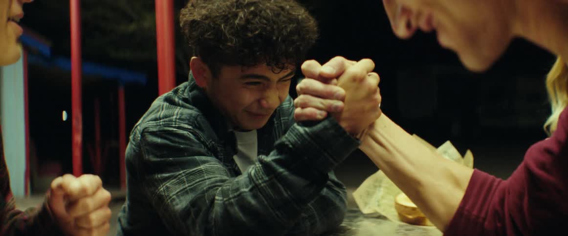 Group of friends arm wrestling on the table of a burger joint at night