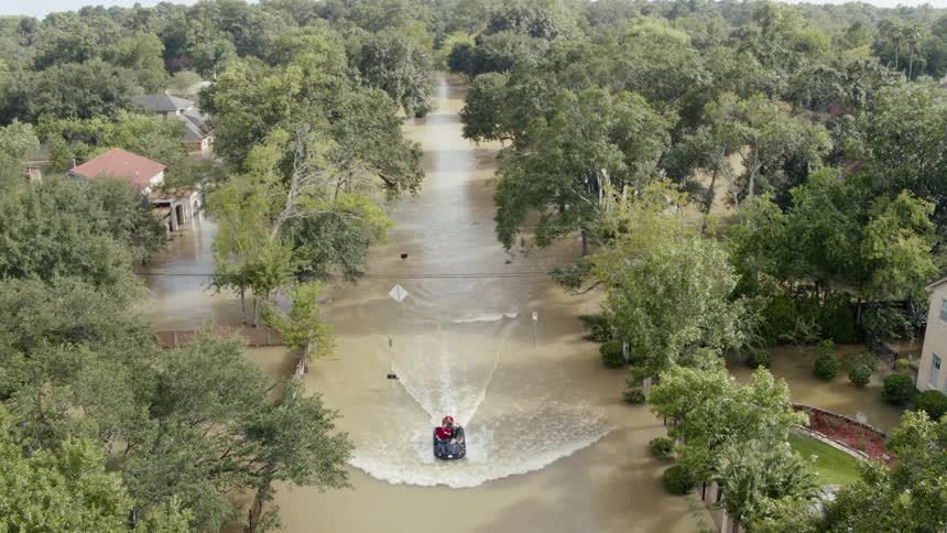 A group of men ride a boat through a flooded neighborhood
