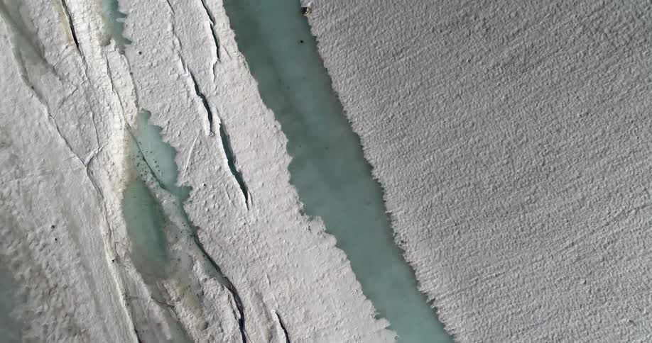 Pale blue river runs through snow and ice