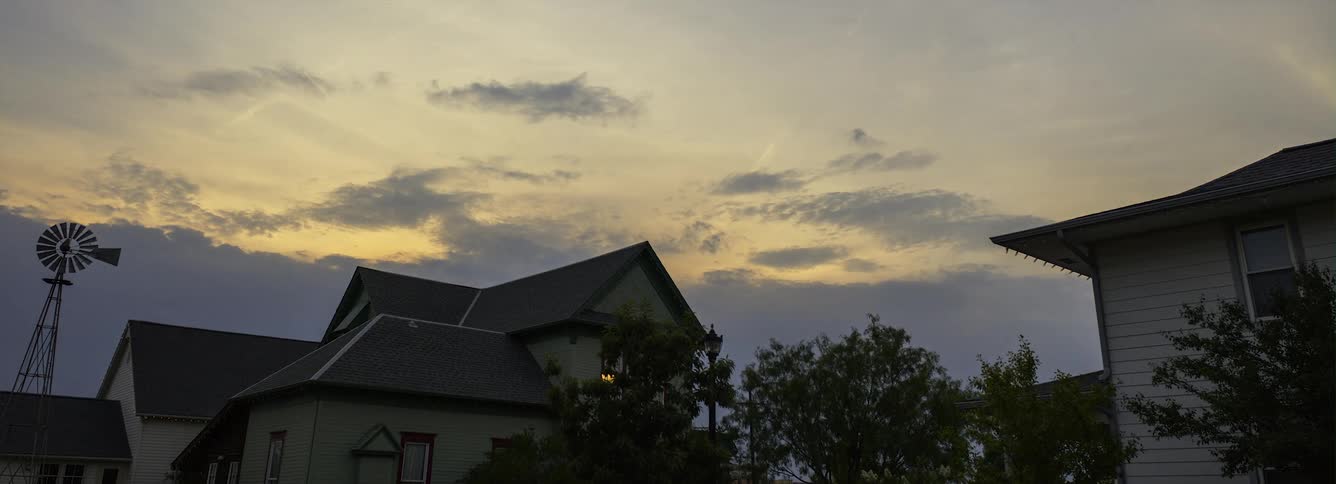 Clouds move across sky over homes near windmill