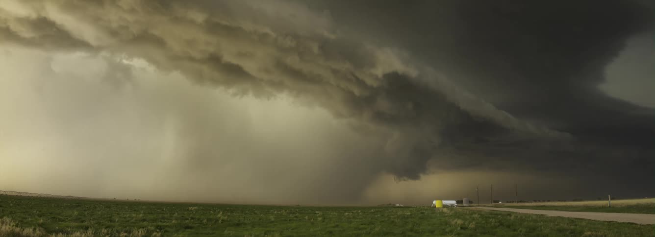 Dark storm clouds rolling over rural fields during a rainstorm