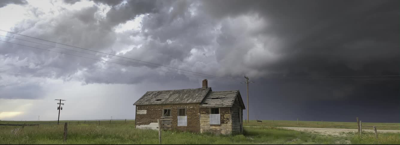 Thick clouds move over a dilapidated building in the countryside during the day