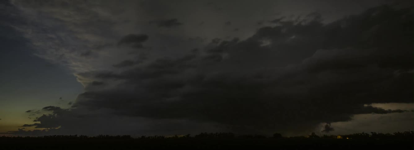 Lightning flashes in the clouds illuminating the dark sky as storm clouds move over a rural area