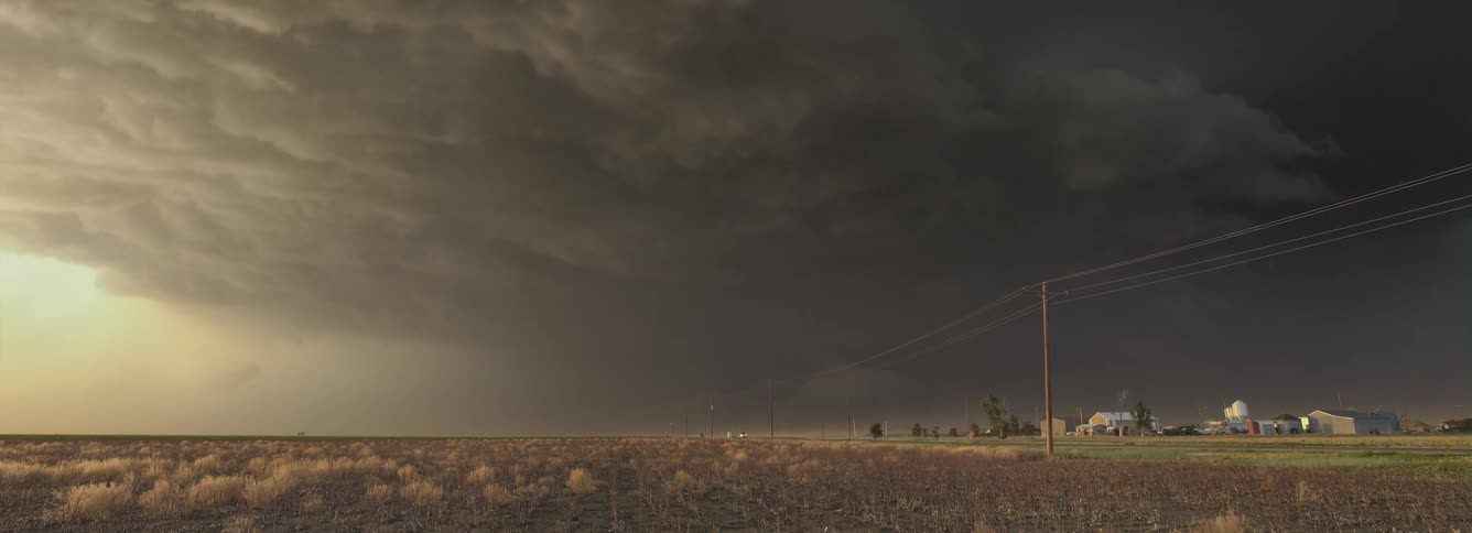 Dark menacing storm clouds move over rural homes as automobiles travel on the road