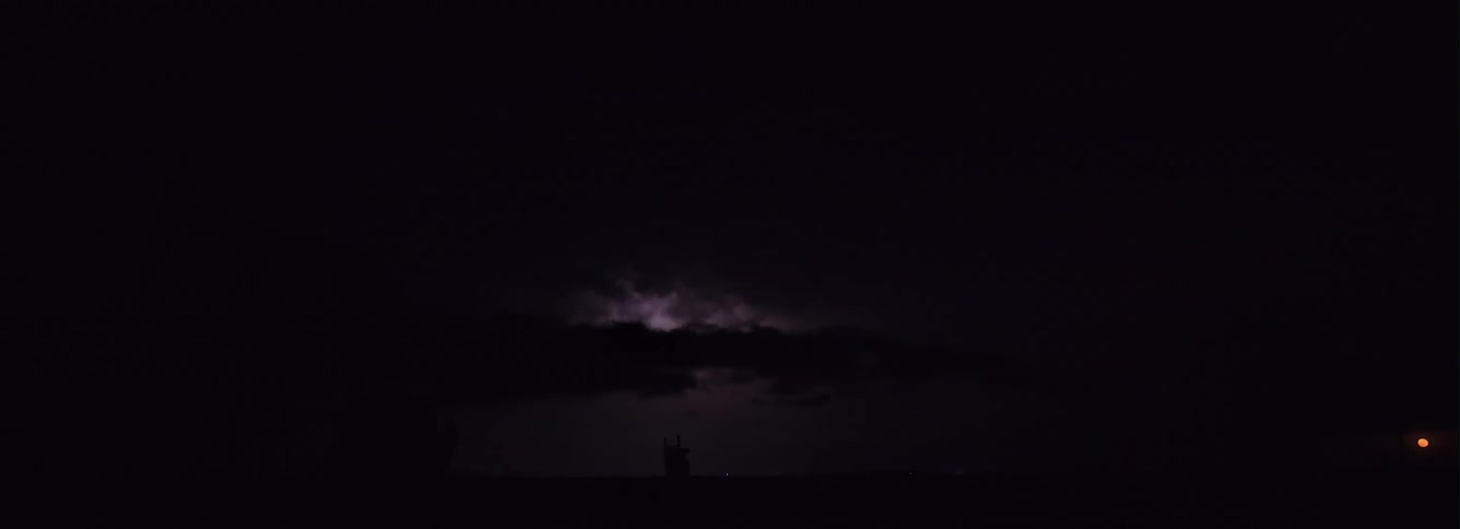 Lightning flashes during thunderstorm reveal silhouette of gas mining rig