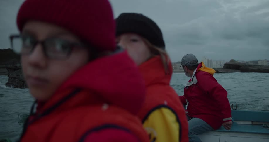 Two boys ride in a boat with their father