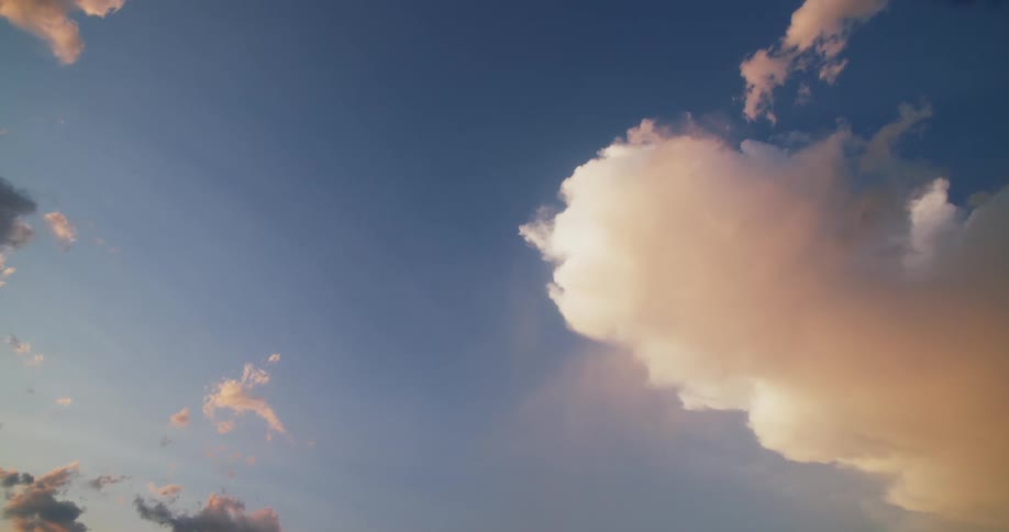 The sun shines on cumulus clouds floating in the blue sky