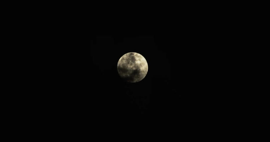 Clouds moving across a full moon at night