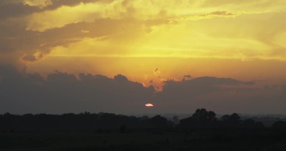 Sun setting behind the clouds on a yellow sky at evening