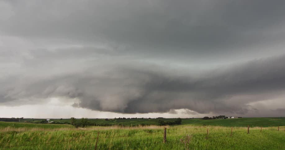 Storm clouds are moving in rotation as they hoover over rural land