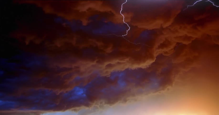 Lightning flashes in red clouds as the sun is setting