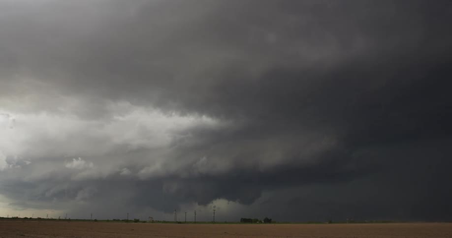 Large storm cloud moving across a field in rural area