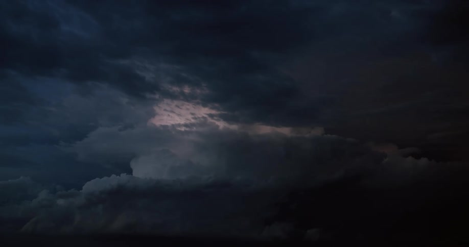 Lightning flashes in the clouds illuminating the dark night sky