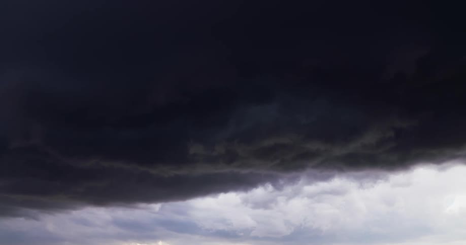 Dark storm cloud moving next to white clouds in the sky