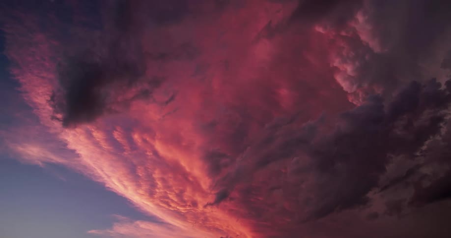 Time lapse of clouds shifting colors at sunset rolling under a blue sky