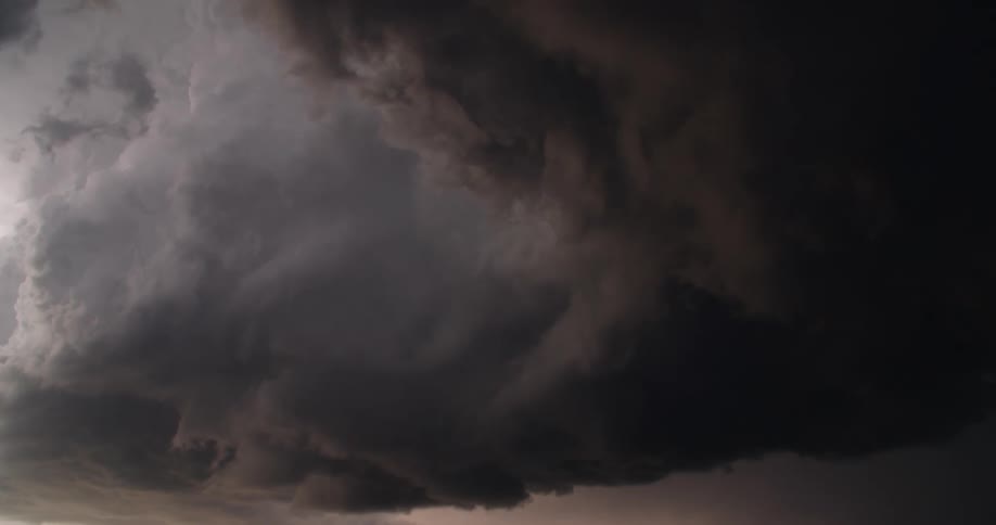 Lightning flashes in dark storm clouds as they move across the sky