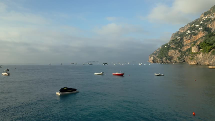 Aerial view of boats floating on water near the mountain on the coast