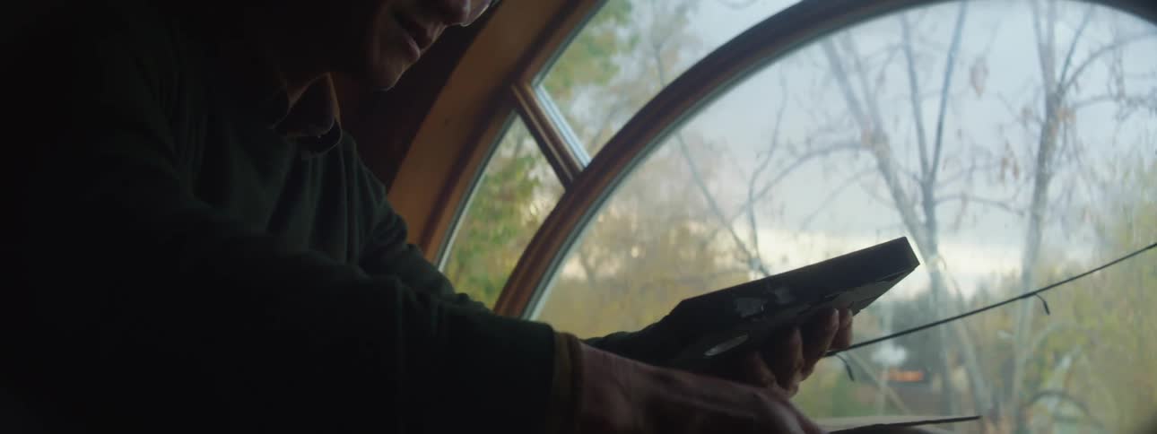 A man unpacks a box and discovers several video tapes inside