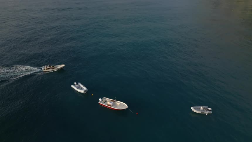 Aerial view of small boats sailing on the calm blue ocean waters close to the coast