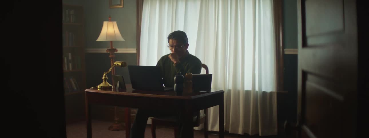Man sitting at a desk on a peaceful room at home working on a laptop