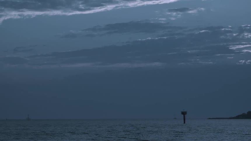 Solitary wooden pole over the calm surface of the ocean at evening