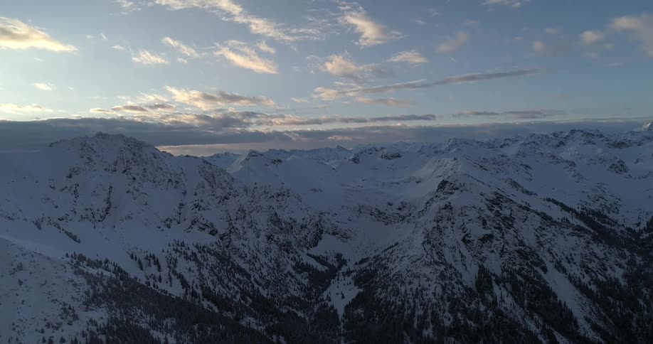 Aerial view of snow covered mountains during dusk is displayed