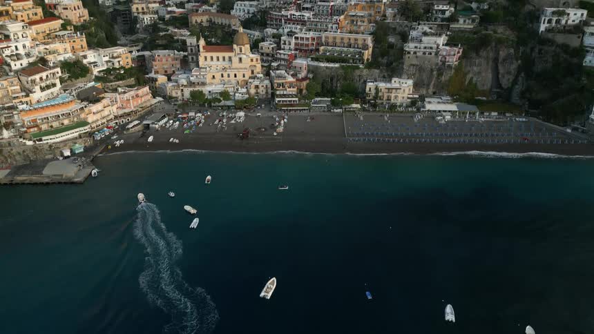 Aerial view of boats sailing towards the docks on a waterfront town in the mountains